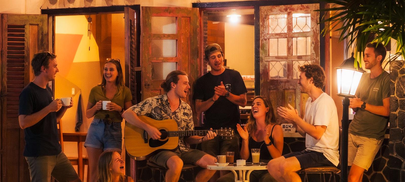 Guests relaxing and playing guitar on the terrace at night.