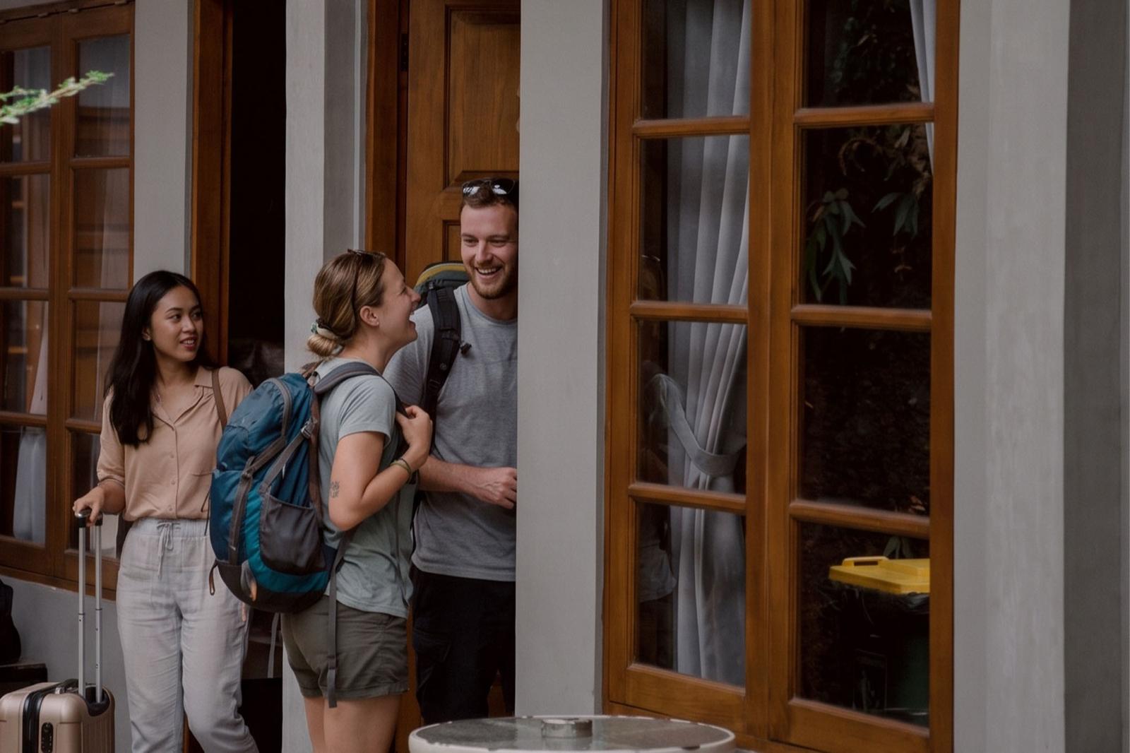 Guests with backpacks and a suitcase arriving at the homestay.