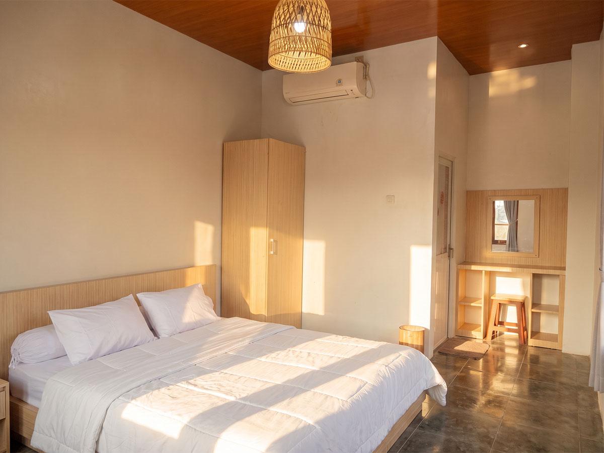 Room with a double bed, rattan lamp, and air conditioning.