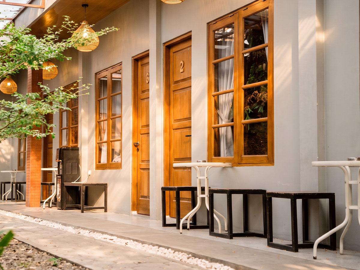 A row of teak-framed room doors facing the pebbled courtyard.