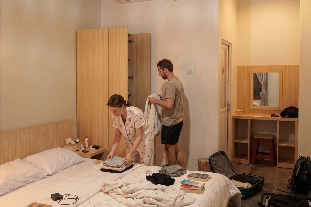 Guests unpacking in the Deluxe 2P room, with wardrobe and vanity desk.